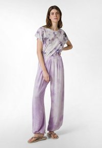 Conjunto de loungewear de dos piezas con tie-dye en tonos púrpura claro; parte superior de manga corta con corte holgado, pantalones con cintura elástica y piernas sueltas y fluidas.