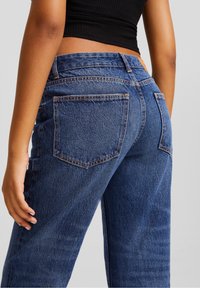 Denim-Jeans in Dunkelblau mit lockerer Passform, zwei Gesäßtaschen, sichtbaren Nähten und einem hohen Bund.