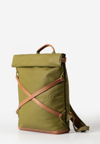 Zaino verde con chiusura roll-top e dettagli in pelle marrone chiaro, caratterizzato da un logo embossato e spallacci a tracolla. Texture liscia e forma strutturata.