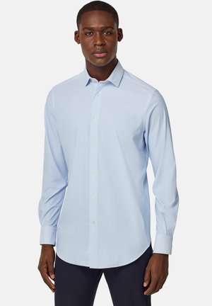 Camicia azzurra chiara con bottoni in tessuto texturizzato, maniche lunghe, colletto classico e orlo curvo. Presenta bottoni e polsini standard.