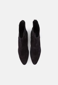 Bottines en daim noir avec un design à bout pointu, des panneaux latéraux élastiques et une texture lisse. Les semelles intérieures portent le lettrage de la marque.