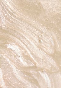 Substance crémeuse et iridescente avec une texture lisse, présentant des motifs doux et tourbillonnants en beige clair et un subtil éclat à travers.