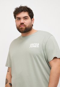 Lysegrønn bomulls T-skjorte med rund hals og korte ermer, prydet med en hvit "JACK & JONES" logo trykt på fronten.