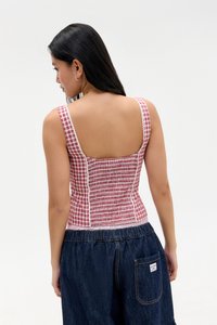 Cropped top na crveno-bijelu kockicu s nabranoj dizajnom, širokim trakama i niskim leđima, u kombinaciji s tamnim trapericama.