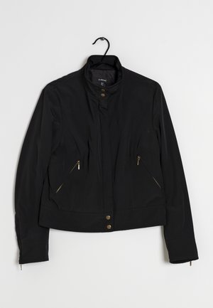 Zwarte jas met een staande kraag, voorzien van gouden ritszakken en drukknoopjes aan de voorkant. Glad materiaal met een getailleerde silhouet.
