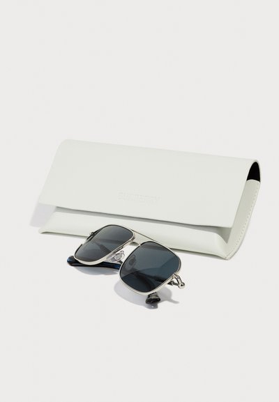 Burberry white leather sunglasses case with embossed logo, containing dark-tinted aviator sunglasses with metallic accents and black temple tips.