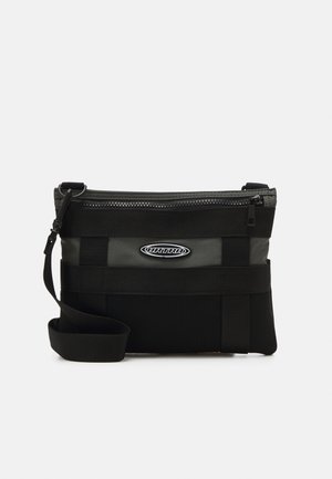 Melnā plecu soma ar rāvējslēdzēja aizdari, ar teksturētām paneļiem, regulējamu siksnu un logotipa uzlīmi. Materiāli ietver gludu un sietu audumu.