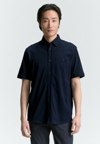Korte mouwen marineblauwe knopshirt met een voorzak, gemaakt van textuurstof, met een standaardkraag en een afgeronde zoom.