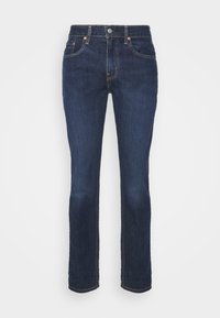 Tmavě modré džíny z denimu se střihem rovného nohu, předními kapsami a kovovým zapínáním. Švy jsou viditelné podél švů.