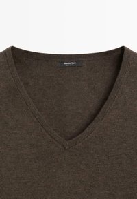 Pull marron à col en V avec un gros plan sur le col et une étiquette indiquant Massimo Dutti fabriqué en Chine.