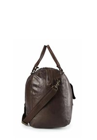 Sac de voyage en cuir marron à forme arrondie, doté de poignées doubles et d'une bandoulière amovible. Texture lisse et fermeture éclair.