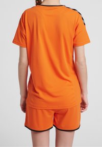 Conjunto de jersey y pantalones cortos atléticos naranjas, hecho de tejido transpirable, con ribetes en negro y un diseño elegante.
