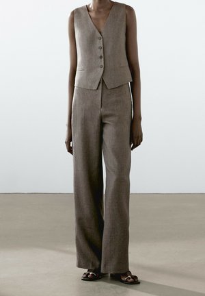 Sleeveless brown buttoned vest paired with matching wide-leg trousers and black open-toe sandals on a standing person.