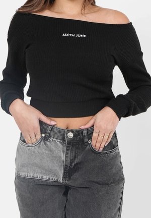Mustat ribbikankaiset off-the-shoulder crop-topit, joissa on valkoinen "SIXTH JUNE" -brändäys, yhdistettyinä korkeavyötäröisiin mustiin farkkuihin.