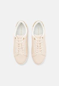 Baskets en cuir beige avec bout arrondi, semelle blanche plate et laçage prononcé. Présente des accents de logo sur la languette et les côtés.