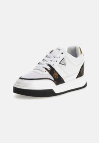 Sneaker bianca con accenti neri e dorati, dotata di un pannello laterale con motivo, suola in gomma testurizzata e logo prominente sulla linguetta e sul lato.
