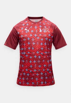 Camiseta deportiva roja de manga corta con patrón de signos más azules, mangas rojo oscuro, logotipo de Puma y un emblema blanco con el número 1 en el pecho.