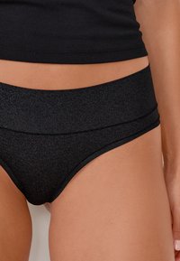 Bikini basso nero con una texture liscia, caratterizzato da un alto della vita e un sottile motivo glitterato in tutto.