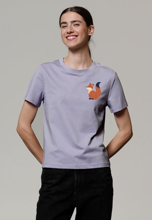 T-shirt lilas à manches courtes en coton, arborant un graphique d'un renard orange stylisé sur le haut du côté gauche de la poitrine.