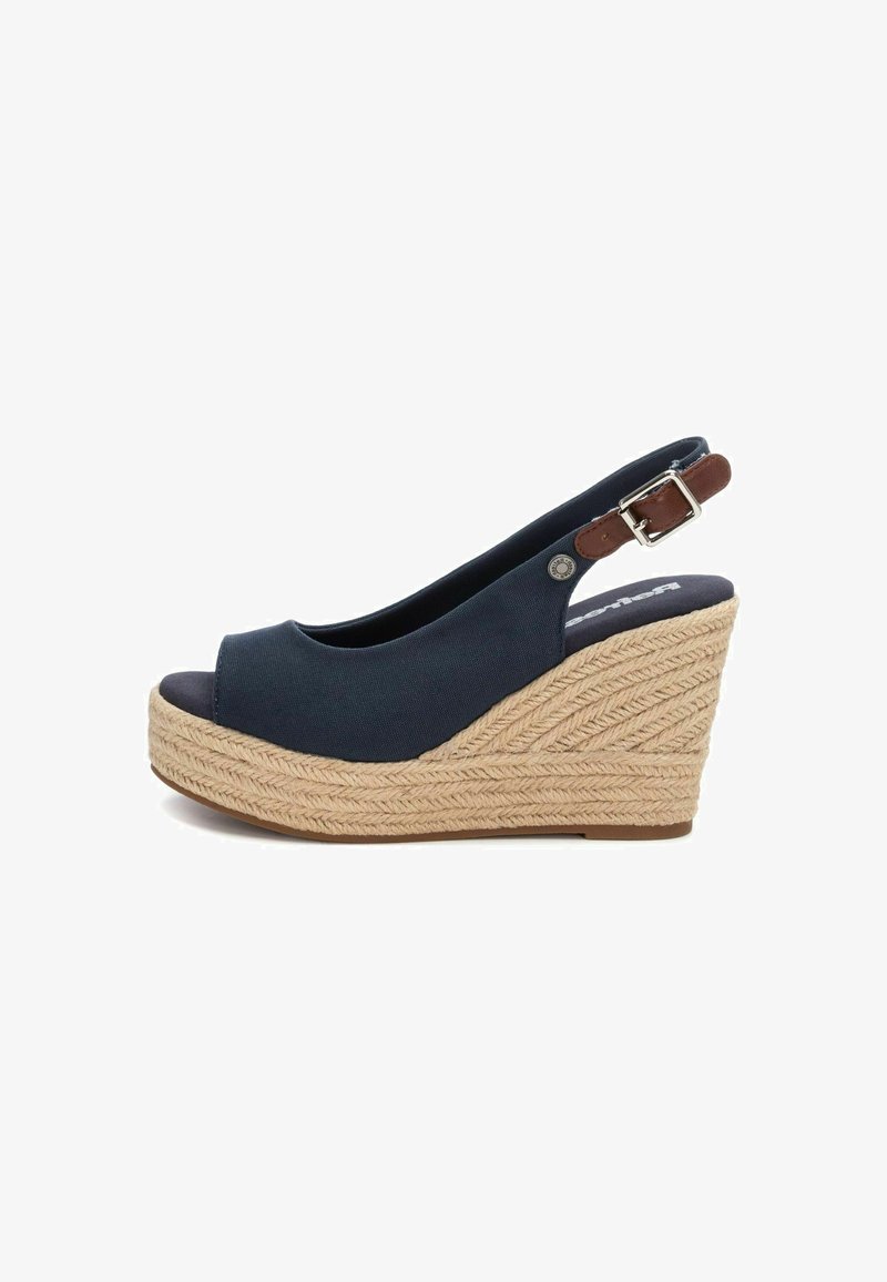 Zapato de cuña tipo slingback en tela azul oscuro con punta redondeada y abierta, que cuenta con una plataforma de cuerda natural trenzada y una pequeña hebilla marrón.