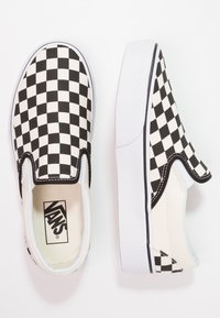 Crno-bijele karirane slip-on cipele s platnenim gornjištem, gumenim potplatom i bijelim rubom, koje imaju teksturirani uzorak i logo unutar.