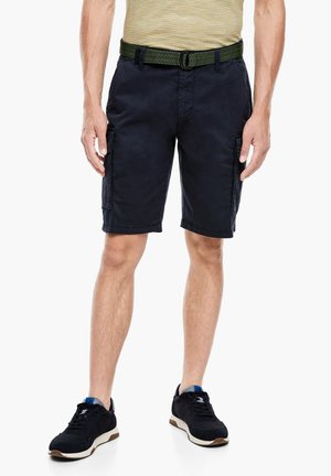 Granatowe szorty cargo z pętelkami na pasek, dwoma kieszeniami bocznymi oraz fakturowanym materiałem. Ubranie połączone z czarnymi trampkami z jasnobrązową podeszwą.