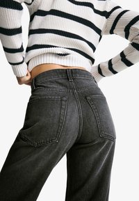 Jeans high-waisted grigio scuro con una vestibilità strutturata, dotati di due tasche posteriori e cuciture a contrasto. Tessuto testurizzato con una finitura pulita.