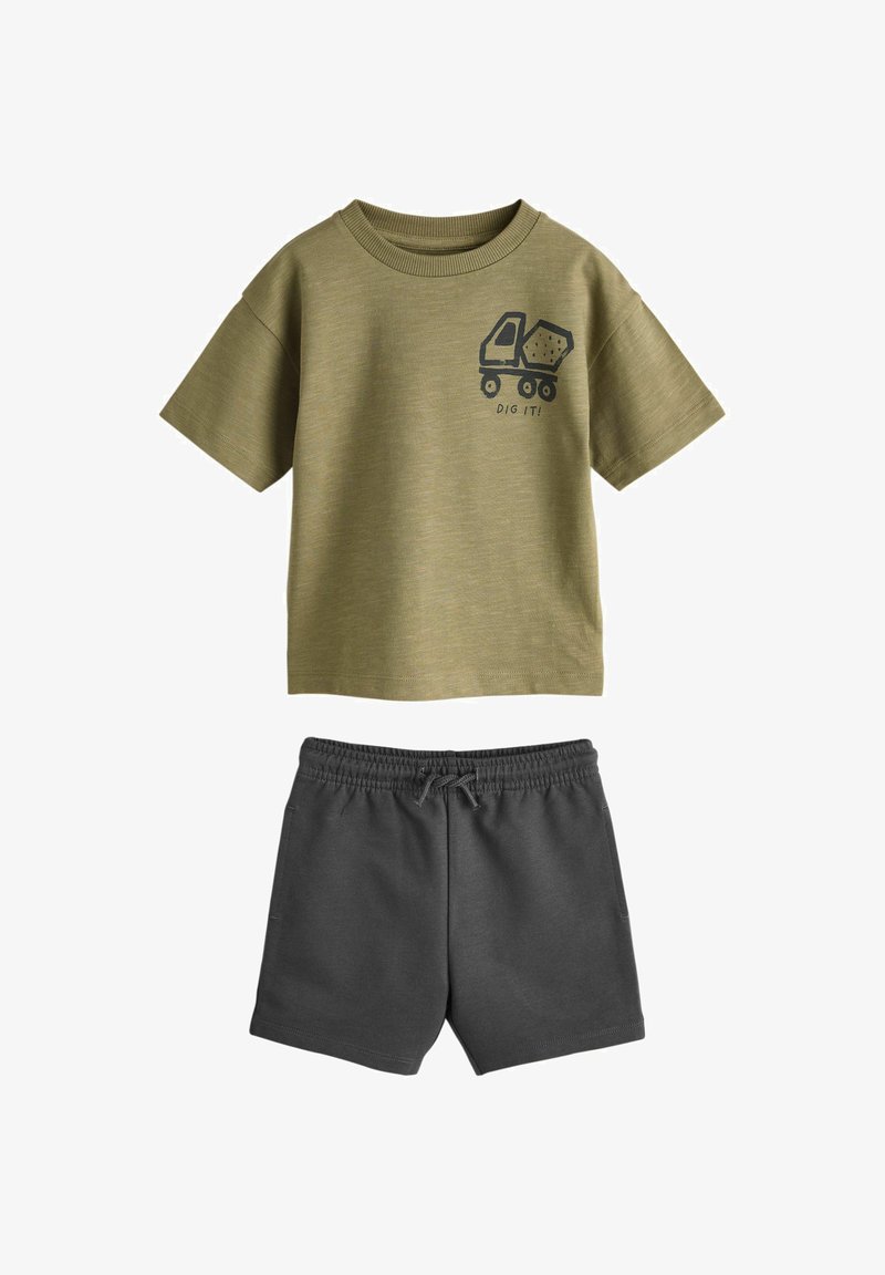 T-shirt vert olive à manches courtes avec un graphique de camion-benne et le texte "CREUSE !" associé à un short gris foncé à taille élastique.