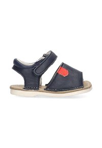 Sandal de cuero azul con una correa de velcro, diseño de punta abierta, suela beige y un parche de acento rojo, con detalles de costura.