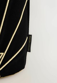 Čierne vrecko z velúrovej látky s prvkami zlatých geometrických liniek, detailným prešívaním a bočnou nálepkou s nápisom „ROCKETT GEORGE“ v metalickom písme.