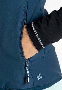 Blaue Softshelljacke mit einem Frontreißverschluss, einer Reißverschlusstasche und einem schwarzen Ärmel mit weißen Nähten. Texturiertem Stoff mit einer taillierten Passform.