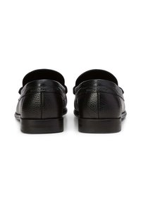 Zwarte leren loafers met een gestructureerde afwerking, platte zolen en minimale stikseldetails aan de achterkant. Ontworpen voor een klassieke silhouet.