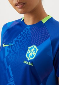 Blue athletic jersey featuring varied patterns, a collared neckline, and neon green accents. Displays the Brazil national team emblem.