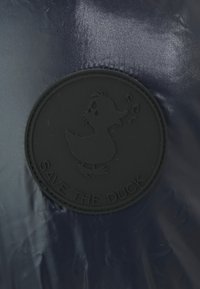 Dunkelblaues, glänzendes Material mit einem runden, schwarzen Gummipatch, das eine Entenillustration und den Text "SAVE THE DUCK" zeigt.