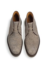 Zapatos grises de fieltro con una textura suave, puntera redonda y cordones de color claro. Forro de cuero marrón y costuras detalladas alrededor de la suela.