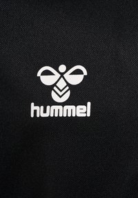 Svart textil med en vit logotyp av en stiliserad bi ovanför ordet "hummel," båda tydligt synliga mot tyget.