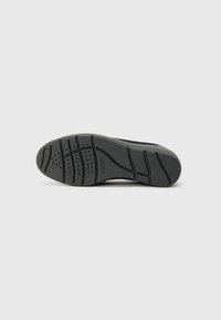 Semelle de chaussure en caoutchouc noir avec des motifs de grip texturés et des trous de ventilation. Surface lisse avec une forme courbée au niveau du talon pour plus de confort.