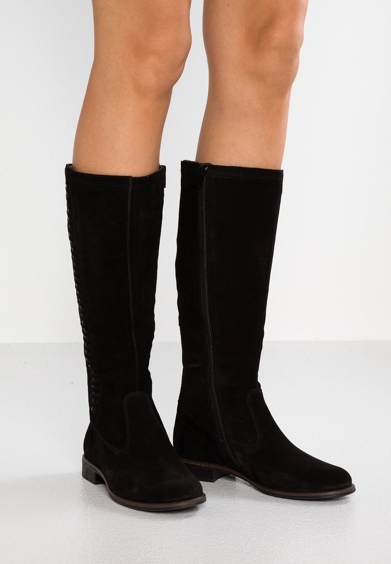 Botas negras de ante hasta la rodilla con una textura suave, cierre de cremallera lateral y costuras decorativas a lo largo de la costura exterior. Suela plana.