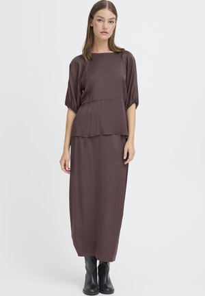 Brun, langærmet, knælang kjole med en afslappet pasform og lagdelt peplum-design, lavet af glat stof. iført sammen med sorte ankelstøvler.