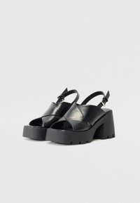 Sorte patentlæder platform sandaler med åben tå, design med krydsede stropper, justerbar ankelspænde og struktureret gummisål.