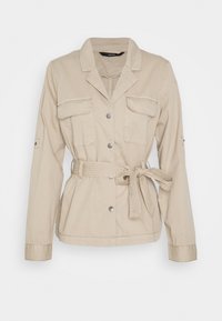 Beige arbejdsjakke lavet af bomuld. Har en krave, to forlommer, sølvfarvede trykknapper og en bælte ved taljen med strukturerede detaljer.