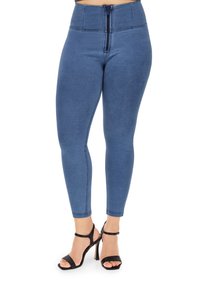 Leggings in denim blu con vita alta, caratterizzati da una zip frontale e dettagli di cucitura. Abbinati a sandali neri con tacco alto e cinturini.