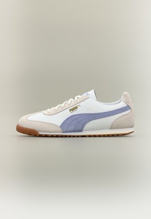 Baskets Puma Arizona blanches et beiges avec une bande bleue et une semelle en gomme, vues de côté sur un fond neutre.