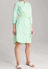 Sukienka na guziki z długimi rękawami, zielono-białe pionowe paski, pasek w talii, długość do kolan, wykonana z lekkiego materiału.