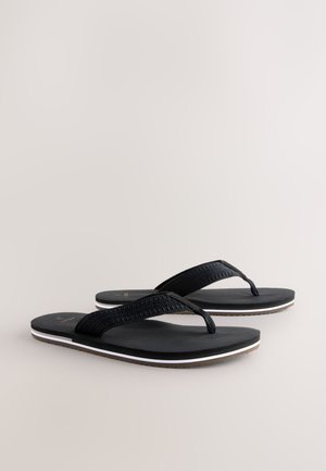 Juodos šlepetės su tekstūruotomis audinio juostelėmis ir guminiu padu, aplink kraštus dekoruotos baltos ir rudos spalvos akcentu.