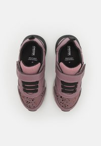 Baskets respirantes roses avec des accents noirs, dotées d'une sangle Velcro, d'une surface texturée et de motifs éclaboussures sur les côtés.