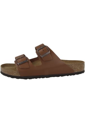 Brown two-strap sandal featuring adjustable metal buckles, a cork footbed, and a rubber sole. Smooth leather upper with an open design.