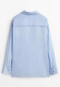 Jasnoniebieska koszula z długim rękawem o teksturowanej tkaninie, zapinana na guziki przy mankietach, z klasycznym kołnierzem. Posiada detal w postaci tylnej karczku oraz prosty dół.