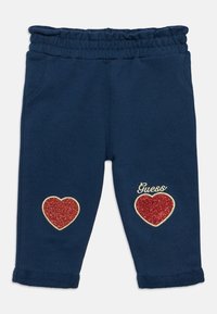 Μπλε ναυτικό φόρμας με ελαστική μέση. Διαθέτει δύο κόκκινες καρδιές με γκλίτερ και το λογότυπο "Guess" κεντημένο σε χρυσό.