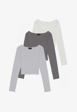 Conjunto de tres tops cortos de manga larga en gris, gris oscuro y blanco. Fabricados en material acanalado con detalles de dobladillo en forma de ondas.